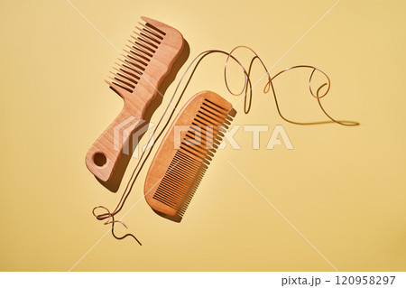 Two wooden combs on a yellow background. 120958297