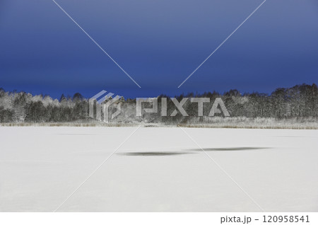 a tranquil winter scene with a frozen snow-covered lake 120958541