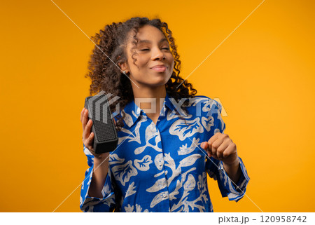 African teenager girl listening music by wireless portable speaker, sound system 120958742