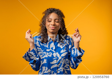 African teenager girl praying crossed fingers on yellow.Young adult begs someone 120958760