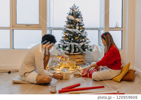 Husband and wife couple lover decorating Christmas tree together while the man helping woman packing decoration boxes. 120959608