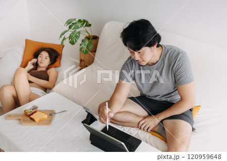 Couple lover, man working at home while woman is having a phone call. Couple lover, man working at home while woman is having a phone call. 120959648