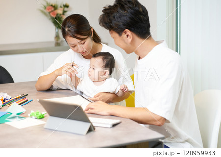 赤ちゃんを抱えた女性とパソコンを操作する男性 120959933