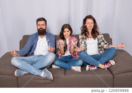 mother father and daughter maditating sit on sofa together, yoga 120959998