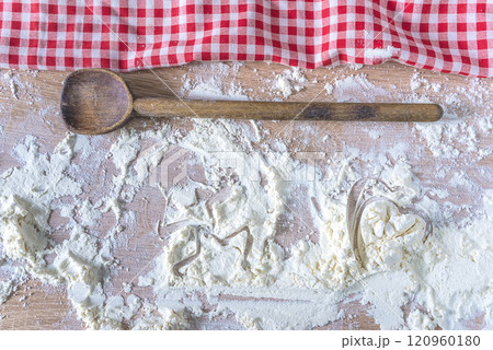 Frame of chechered napkin and old wooden spoon on flour covered wooden background Frame of chechered napkin and old wooden spoon on flour covered wooden background 120960180