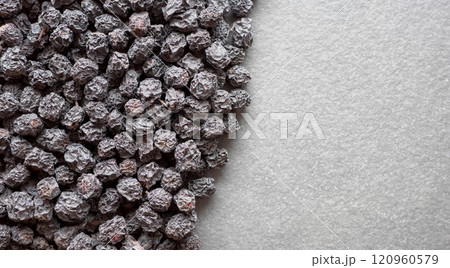 Close up photo of organic dried aronia berries on a dark slate background, selective focus. Close up photo of organic dried aronia berries on a dark slate background, selective focus. 120960579