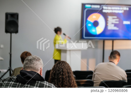 Business professional giving presentation during conference with attentive audience Business professional giving presentation during conference with attentive audience 120960806