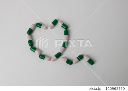 Multicolored heart-shaped medical capsules in close-up on a white background. Minimalistic design. The concept of love and care. 120962360