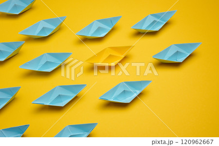 Group of paper boats rushing forward on yellow background, achieving goals Group of paper boats rushing forward on yellow background, achieving goals 120962667