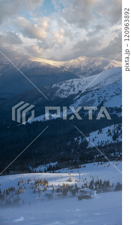 Alpine resortr ski lift with seats going over the sunset mountain skiing slopes in extremally windy weather Alpine resortr ski lift with seats going over the sunset mountain skiing slopes in extremally windy weather 120963892