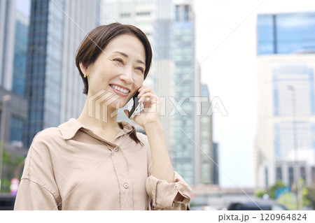 外でスマートフォンで電話する女性 120964824