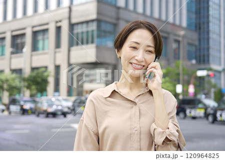 外でスマートフォンで電話する女性 120964825