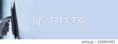 Worker uses a trowel to apply microcement on a wall for repair. Banner for your text. 120965881