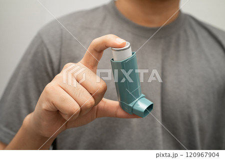 Asthma and chronic obstructive pulmonary disease COPD, Asian young man using metered dose inhaler MDI. 120967904