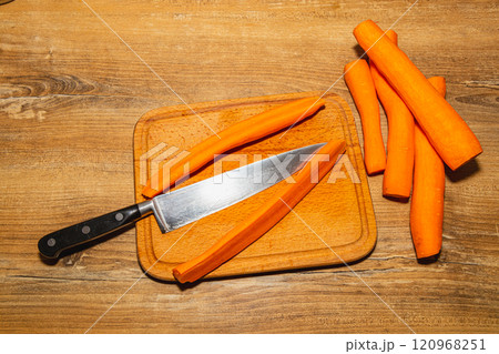 Carrots cut into pieces on a kitchen board, next to a knife 120968251