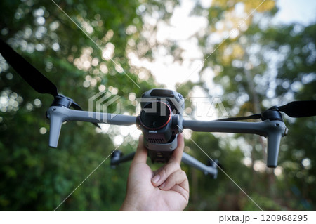 Drone with camera in hand before flying, bokeh background in green forest. Drone with camera in hand before flying, bokeh background in green forest. 120968295