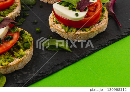 Rice cakes with mozzarella avocado spinach onion on a black and green background Rice cakes with mozzarella avocado spinach onion on a black and green background 120968312