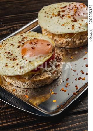 Freshly fried egg on rice bread with tomato and feta cheese on a metal tray Freshly fried egg on rice bread with tomato and feta cheese on a metal tray 120968324