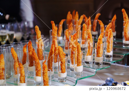 a glass with sauce and battered shrimps on the buffet table. 120968672