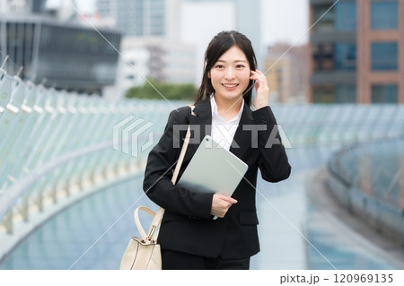 オフィス街でスーツを着てタブレットを持つビジネスウーマン オフィス街でスーツを着てタブレットを持つビジネスウーマン 120969135