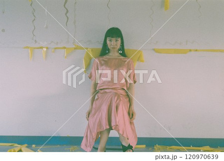 椅子に座りながらカメラ目線を送るロングヘアのピンクのドレスの女性 120970639