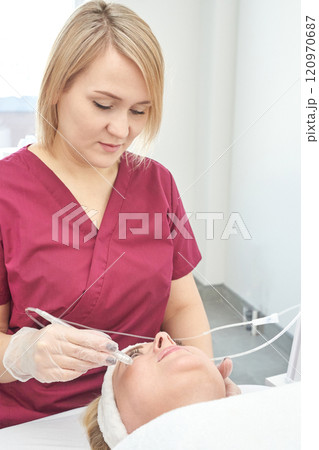 Female caucasian adult performing cosmetic procedure in medical setting 120970687