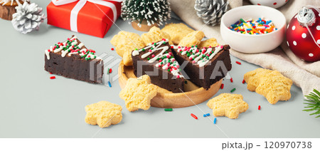 Chocolate brownies and cookies in wooden tray with christmas decoration on pastel green table Chocolate brownies and cookies in wooden tray with christmas decoration on pastel green table 120970738