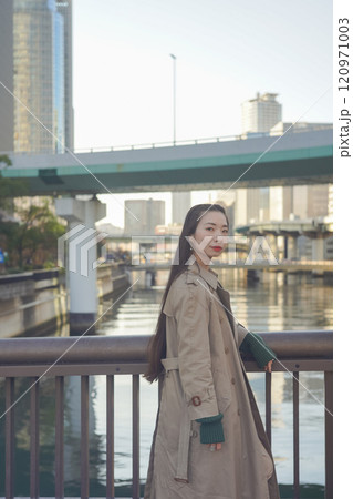 夕暮れの海岸線の線路沿いの柵にもたれかかっている外国人女性 120971003