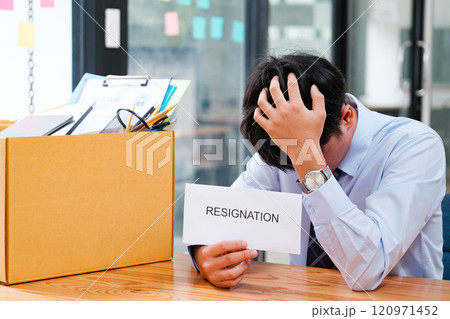 Disappointed Businessman Holding Resignation Letter and Packing Belongings. Disappointed Businessman Holding Resignation Letter and Packing Belongings. 120971452
