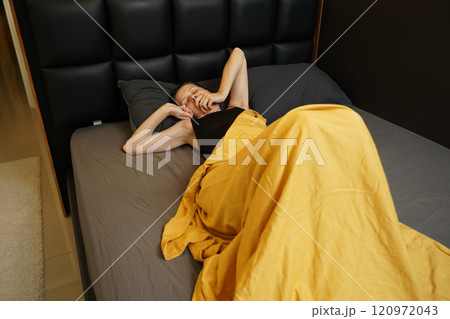 A woman sleeping peacefully under a yellow blanket A woman sleeping peacefully under a yellow blanket 120972043