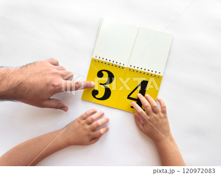 Parent and child learning numbers together with a yellow flip book 120972083