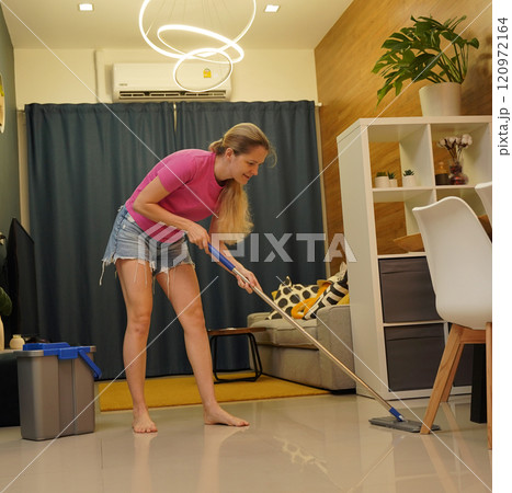 A woman is cleaning her living room at home A woman is cleaning her living room at home 120972164