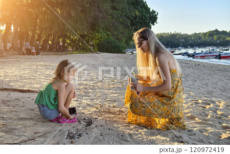 A mother and her daughter as they collect shells together  120972419