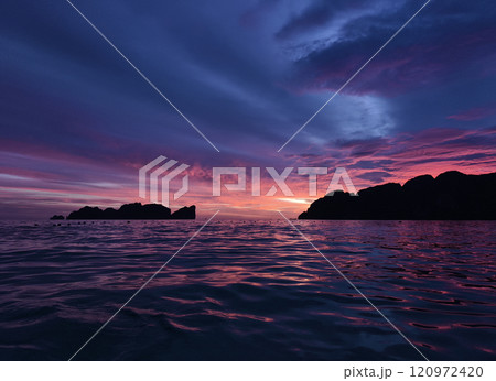 A stunning sunset is casting vibrant hues of color over a tranquil ocean 120972420