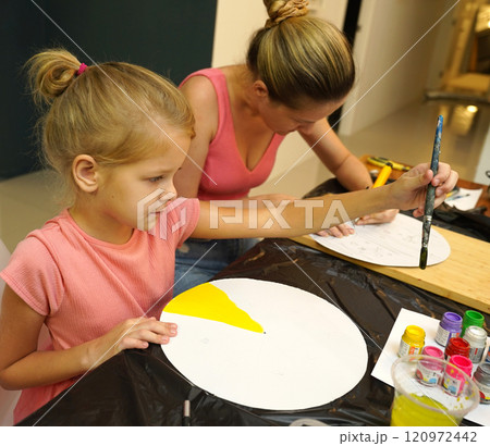 A mother and her young daughter engage in a colorful painting activity  120972442