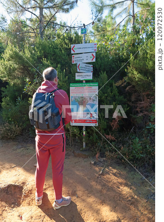 Sestri Levante, Italy - November 10, 2024. Man look at on map. Hiking in mountain. Trail marker on rock against background of tree foliage and bushes.  120972530