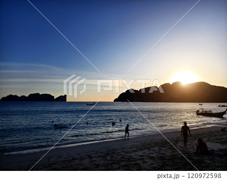 A stunning sunset is casting vibrant hues of color over a tranquil ocean 120972598