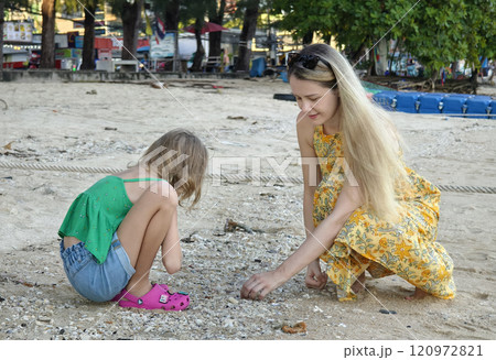 A mother and her daughter as they collect shells together A mother and her daughter as they collect shells together 120972821