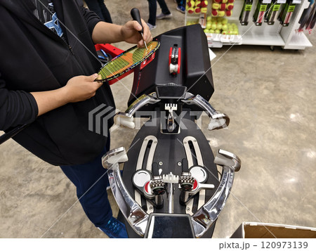 Strings a badminton racket on a racket stringing machine. 120973139