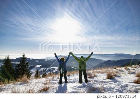 Rear view of active seniors standing in the middle of winter nature with open arms. 120973514
