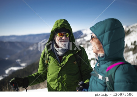 Portrait of active seniors enjoying nature. Romantic winter hike for an elderly couple in snowy mountains. 120973590
