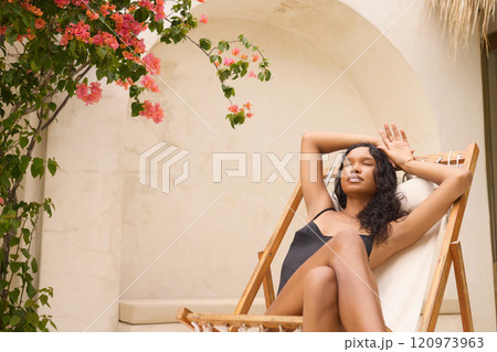 Relaxed Woman Sunbathing in Lounge Chair Amidst Vibrant Blooms Relaxed Woman Sunbathing in Lounge Chair Amidst Vibrant Blooms 120973963