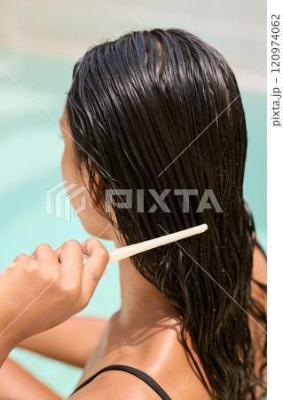 Woman Gently Combing Wet Hair by Poolside for Relaxation and Hair Care 120974062