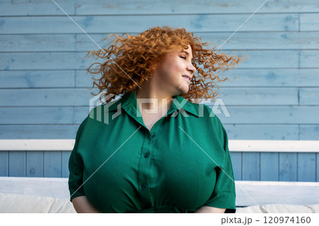 Beautiful Happy Plus Size Woman Enjoying Life, Dancing and Shaking Hair with Joy, Confidence and Positive Emotions Outdoors Against Blue Background 120974160