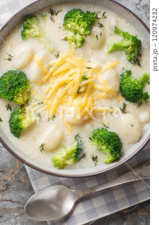 Classic broccoli cheese soup with tender gnocchi closeup on the plate on the table. Vertical top view Classic broccoli cheese soup with tender gnocchi closeup on the plate on the table. Vertical top view 120974282