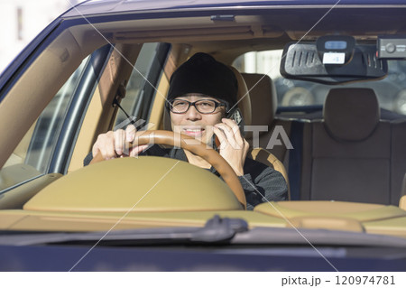 スマホで通話しながら運転する男性（イメージ） 120974781