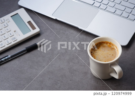 淹れたてのコーヒー(カフェラテ)を飲みながら、電卓とノートパソコンでデスクワークをしているイメージ 淹れたてのコーヒー(カフェラテ)を飲みながら、電卓とノートパソコンでデスクワークをしているイメージ 120974999