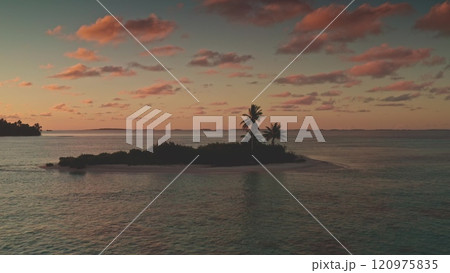 Breathtaking aerial view of small island in Tikehau atoll, French Polynesia, vibrant colorful sunset sky, palm trees and tranquil turquoise waters. Remote wild nature paradise, exotic summer travel 120975835