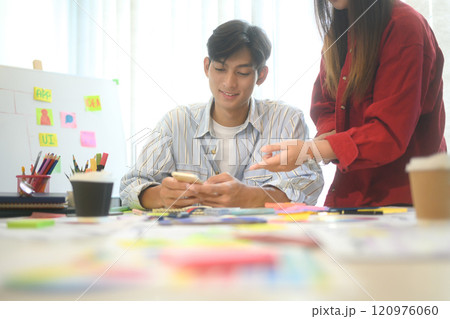 Close up of designers discussing app layout and interface wireframes during a brainstorming session 120976060