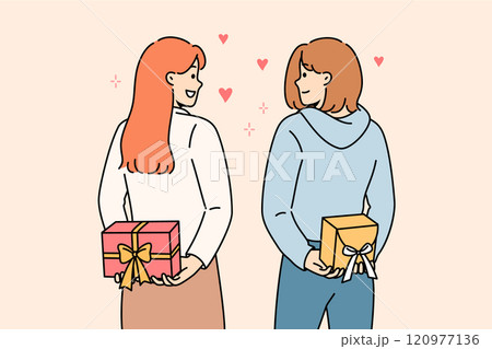 Positive girls hold gifts behind their backs and look at each other lovingly, showing sympathy Positive girls hold gifts behind their backs and look at each other lovingly, showing sympathy 120977136